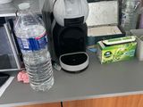 une cafetière posée sur le plan de travail de la cuisine, à côté d'un verre d'eau