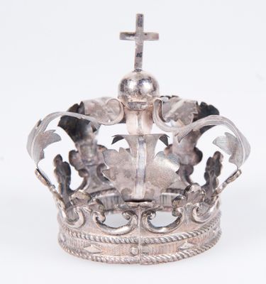 une couronne en argent surmontée d'une croix, posée sur un fond blanc