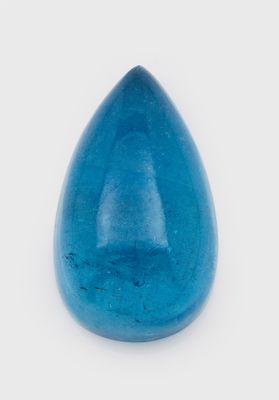 un gros plan d'un objet en verre bleu en forme de larme posé sur une surface blanche