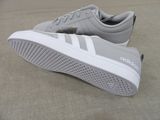 grey and white adidas sneakers on a beige surface