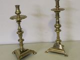 une paire de bougeoirs anciens en laiton posés sur un socle, sur une table