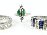 three rings and a ring with different colored stones on a white surface