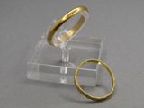 une bague en or et une autre bague en or posées sur un socle transparent