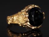 une bague en or sertie d'une pierre noire sur un fond noir