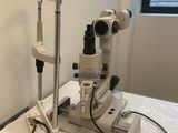 une table blanche sur laquelle est posé un microscope, dans une pièce