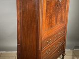 a tall wooden cabinet with a marble top on a tiled floor