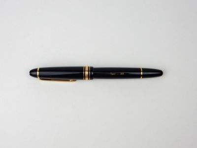 un stylo plume noir et doré posé sur une surface blanche