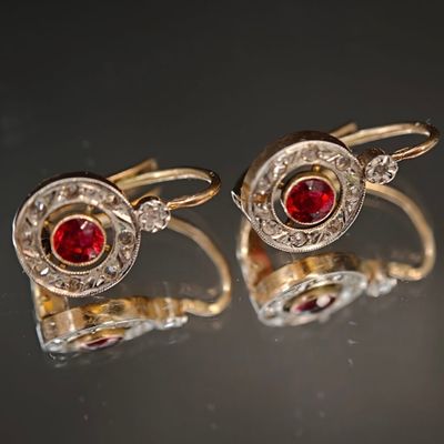 une paire de boutons de manchette en rubis et diamants posés sur une surface réfléchissante