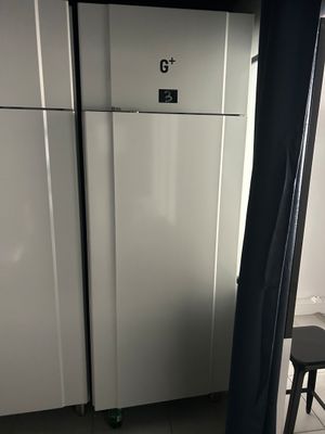 un réfrigérateur blanc et un tabouret noir dans une cuisine