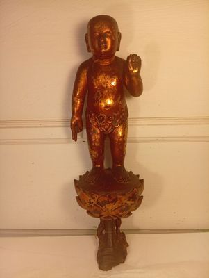 une statue en or représentant un bébé tenant une fleur
