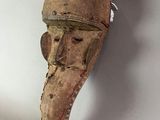 a wooden mask hanging on the wall next to a white wall