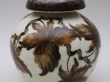 un vase blanc orné de fleurs marron, posé sur un fond blanc