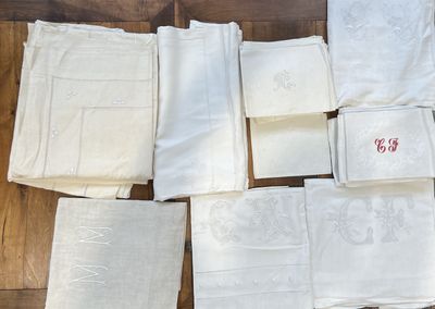 many white napkins on a wooden floor with a red monogram
