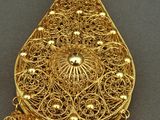 an image of a gold broochle with pearls and a tassel