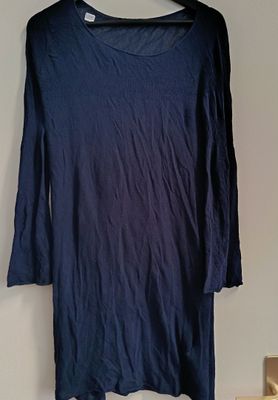 blue long sleeved shirt hanging on a hanger on a wall