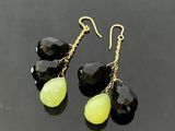 une paire de boucles d'oreilles noires et jaunes posées sur une surface noire