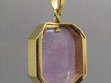un gros plan sur un pendentif en or orné d'une pierre violette