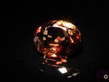 a close up of an orange diamond on a black surface
