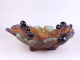 a small bowl with black beads on it on a white surface