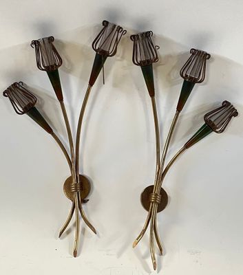 three metal wall sconces with flowers on them mounted on a wall