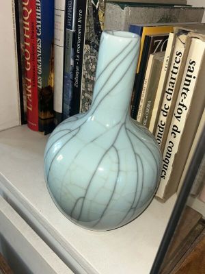 un vase posé sur une étagère à côté de quelques livres