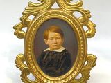 portrait d'un jeune garçon vêtu d'une robe noire, dans un cadre doré
