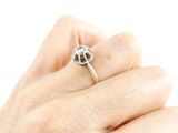 a woman ' s hand holding a ring with a flower on it