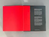 a red and black book open to a page of text