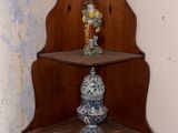 une étagère d'angle placée dans un coin de la pièce, sur laquelle se trouve un vase