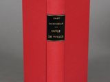 a red book sitting on top of a table next to a gray wall