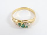 a close up of a gold ring with two emerald stones