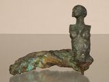 statue d'une femme assise sur un rocher posé sur une table en verre