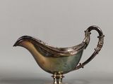 an antique silver plated sauce boat on a stand