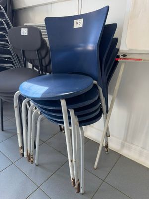 four blue chairs in a room with a white board