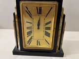 une horloge noire et dorée avec des chiffres romains