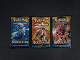 trois paquets de cartes à collectionner Pokémon posés sur une surface noire