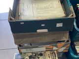 une pile de journaux posée par terre à côté d'un bac vert