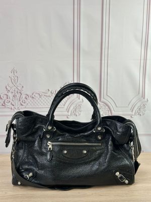 un sac à main en cuir noir posé sur une table en bois