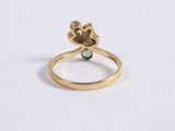 a close up of a gold ring with a green stone