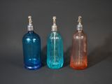 three different colored bottles sitting next to each other on a table
