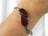 someone is wearing a bracelet with two red glass beads on it