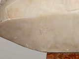 a white marble sculpture of a boat on a wooden base