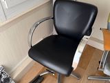 une chaise noire placée devant une fenêtre dans une pièce