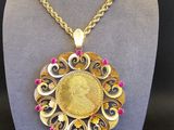 un gros plan d'un collier orné d'une pièce d'or, porté par un mannequin