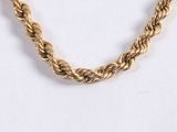 a close up of a gold rope necklace on a white surface