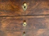a wooden chest of drawers with brass hardware on top of it