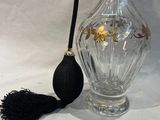 un vase en verre muni d'une anse noire, à côté d'un pinceau noir