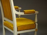 an old chair with a yellow seat and a wooden arm rest