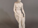 statue d'une femme assise sur un rocher, les mains dans les poches