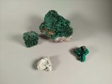 some green crystals and a rock on a white surface